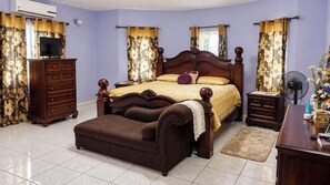 A bedroom with a bed, a dresser, a TV, and a fan. - Montego Bay 3-Bed Home, Sleeps 6 Parking & Garden (Montego Bay)
