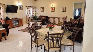 A living room with a dining area, a television, and a staircase. - Montego Bay 3-Bed Home, Sleeps 6 Parking & Garden (Montego Bay)
