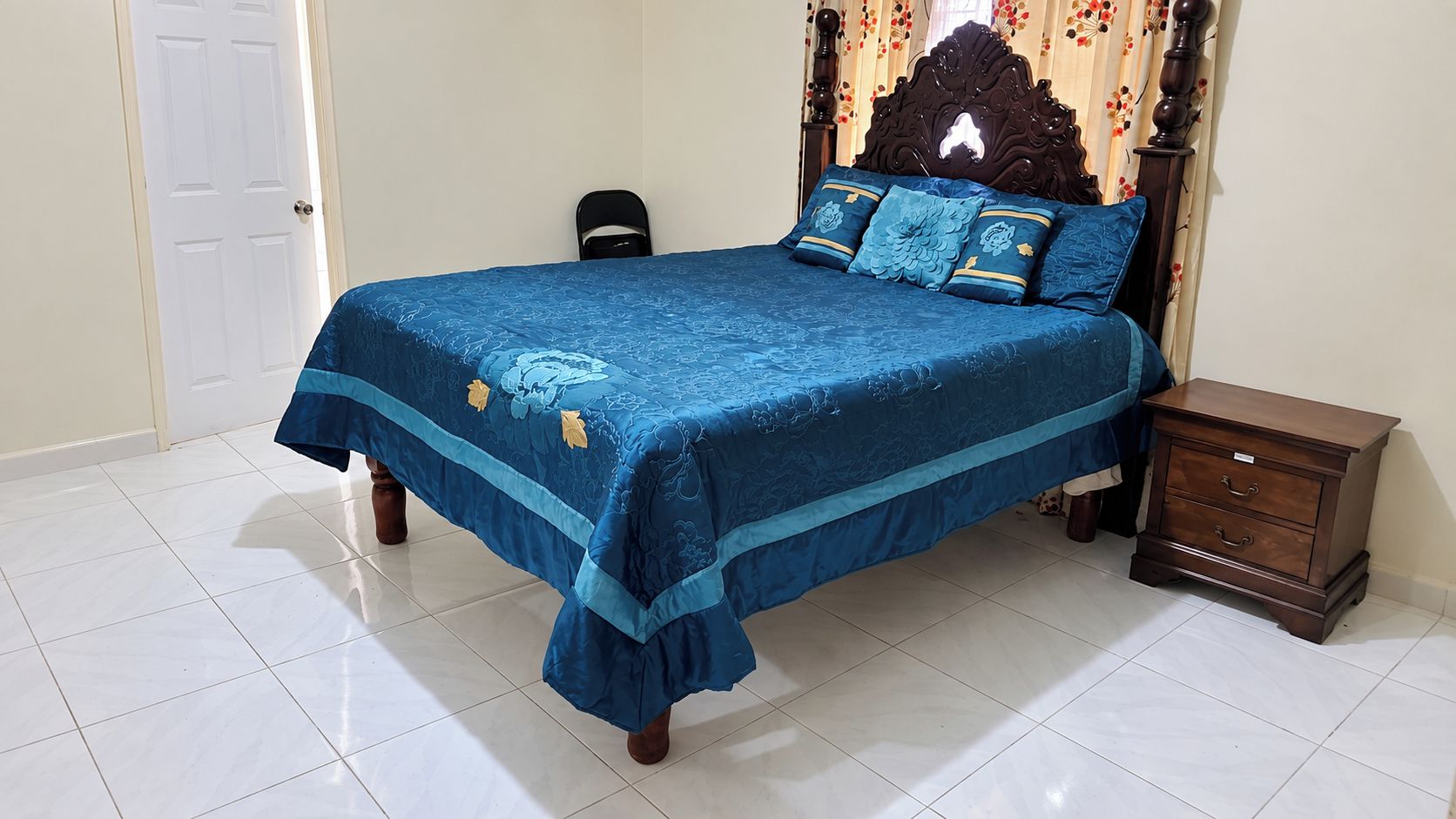 A bedroom with a bed, a nightstand, and a door.
