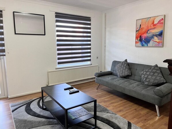 A living room with a grey sofa, a black coffee table, and a modern abstract painting on the wall.