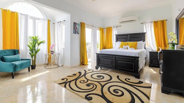 A bedroom with a bed, a ceiling fan, a desk, and a chair. - Luxury Sea-View Townhouse, Pool , Ocho Rios (Ocho Rios)