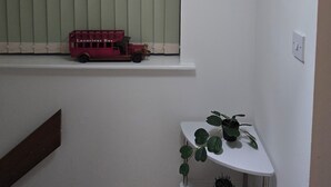 A room with a window, a red toy bus, a white table, and a hanging light fixture. - Emerald Apartment Sleeps 4 with Parking (London)