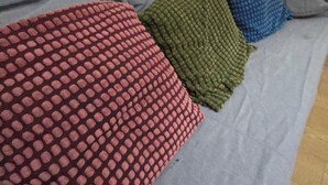 A bed with a grey sheet and three pillows in red, green, and blue. - Emerald Apartment Sleeps 4 with Parking (London)