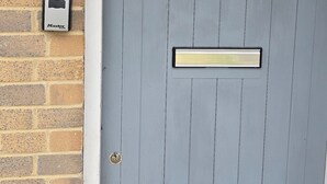 A grey door with a peephole, a mail slot, and a small window with a grid pattern. - Emerald Apartment Sleeps 4 with Parking (London)