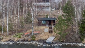 Una cabaña con un muelle que se adentra en un lago, rodeada de bosque.