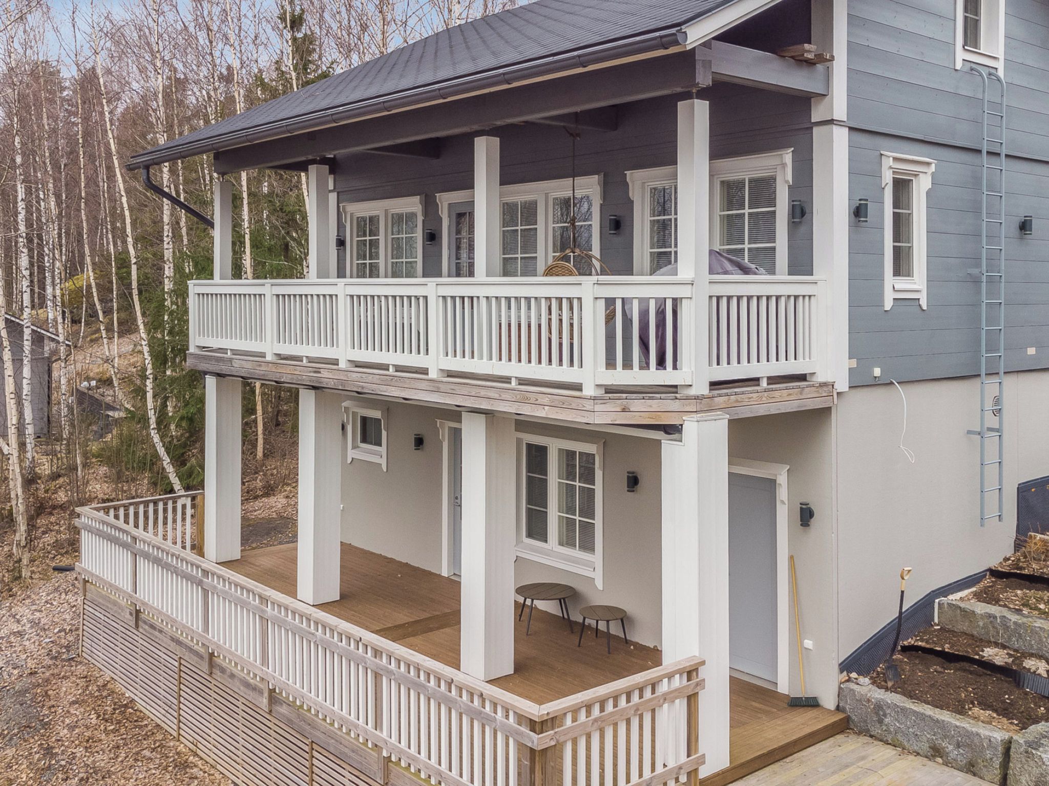 A two-story house with a balcony, a covered porch, and a small outdoor seating area.