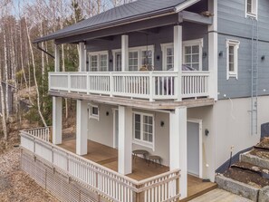 Une maison à deux étages dotée d’un balcon, d’un porche couvert et d’un petit espace extérieur aménagé pour s’asseoir.
