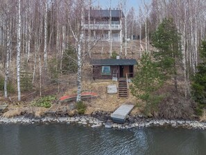Eine Holzhütte mit einem Steg, der in einen See führt, umgeben von einem Wald.
