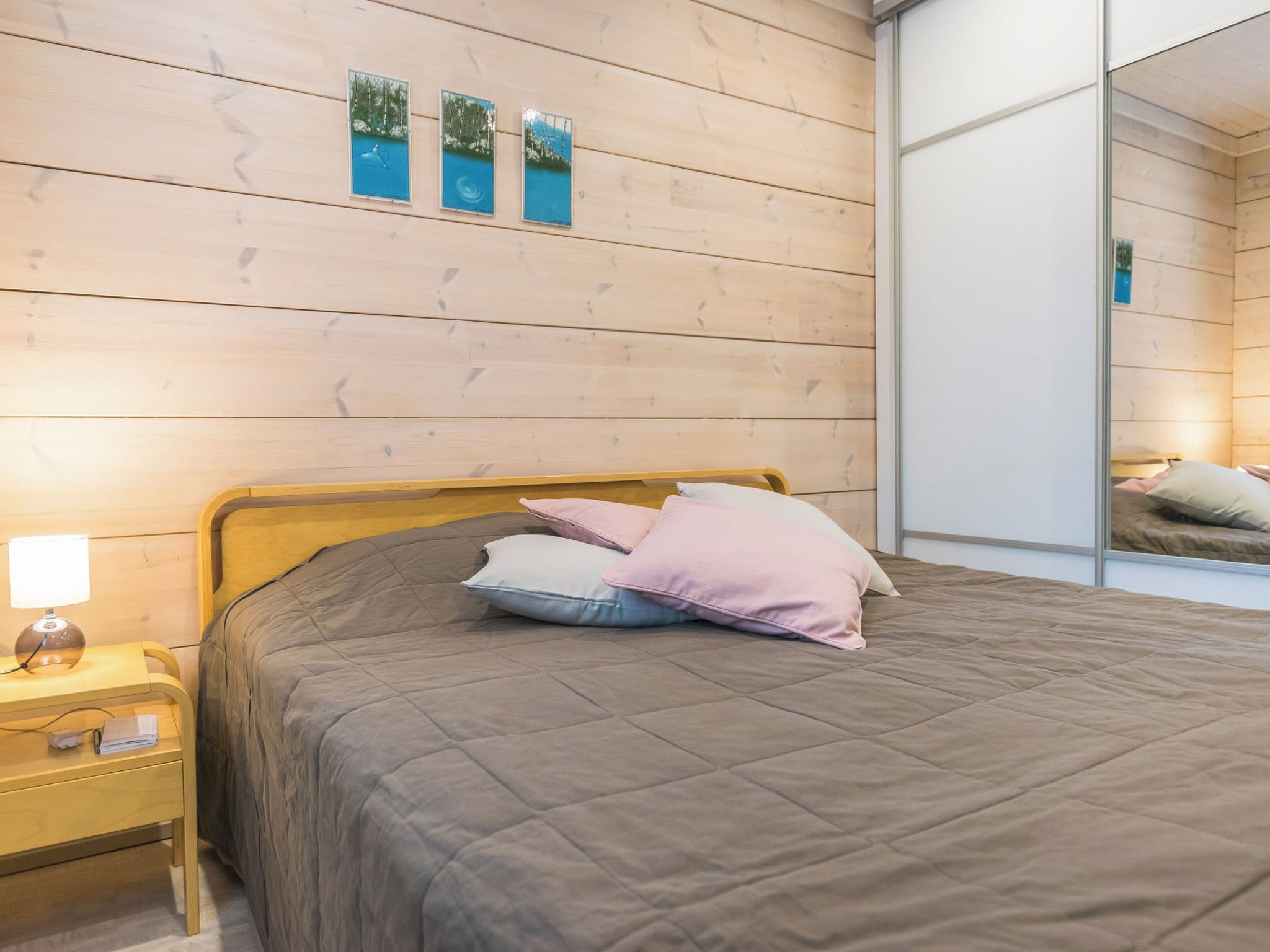 Ein Schlafzimmer mit einem hölzernen Kopfende, einem Bett mit gesteppter Bettdecke und einem Nachttisch mit Lampe.