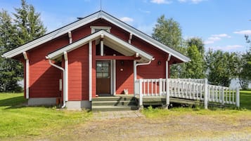 Ein rotes Holzgebäude mit einer Veranda und einem weißen Zaun.