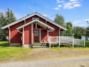 A red wooden building with a porch and a white fence.