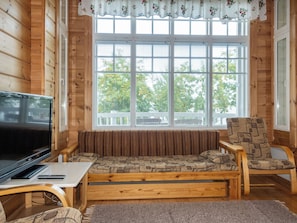 A cozy cabin interior with a wooden bench, a television, and a window with blinds. - Mansikkaranta 3, osittain esteetön by Interhome (Pyhäjärvi)