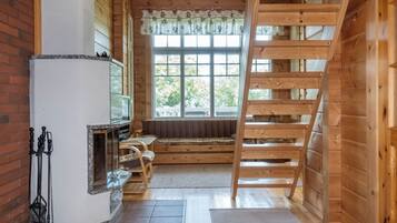 Un intérieur en bois avec une cheminée, une fenêtre donnant sur un beau paysage et une échelle en bois.