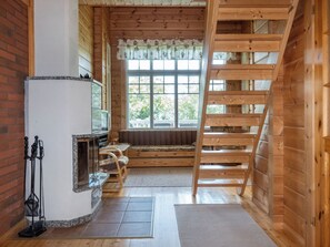 A wooden interior with a fireplace, a window with a view, and a wooden ladder. - Mansikkaranta 3, osittain esteetön by Interhome (Pyhäjärvi)
