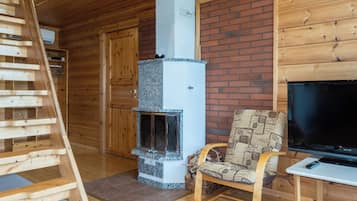 Ein Holzinnenraum mit Kamin, Fernseher und einem Sessel.