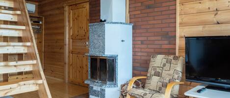 A wooden interior with a fireplace, a TV, and a chair.