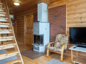 A wooden interior with a fireplace, a TV, and a chair.