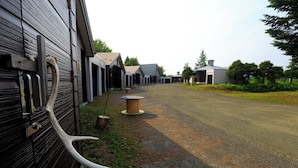 A row of wooden buildings with a gravel path leading to a central area with a wooden post. - STARRY SKY COTTAGE 17 (Kitami)