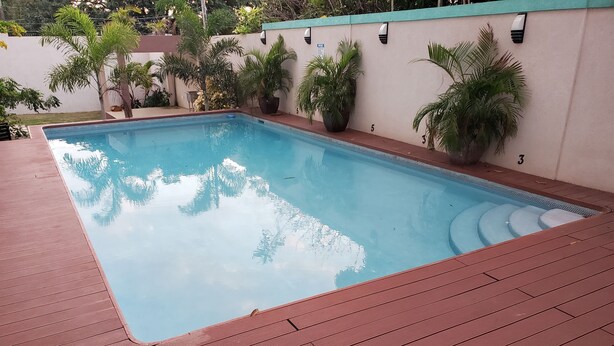Une piscine rectangulaire entourée d’une terrasse en bois.
