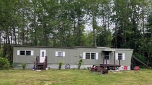 Ein Bungalow mit Veranda, kleiner Terrasse und Kopfsteinpflasterauffahrt.