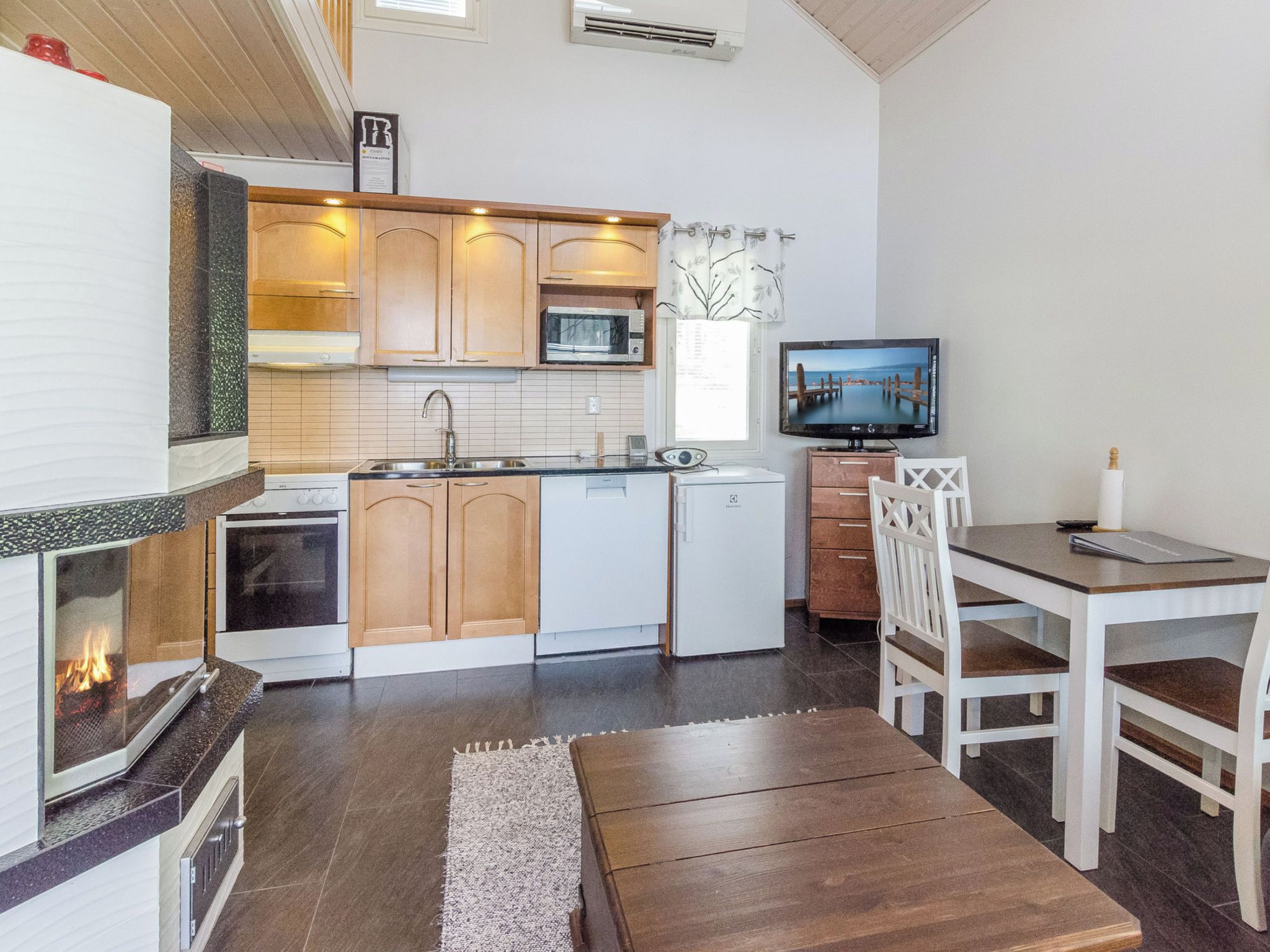 A compact kitchen with a microwave, stove, and sink. There's a small dining area with a table and chairs.