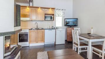 A compact kitchen with a microwave, stove, and sink. There's a small dining area with a table and chairs.