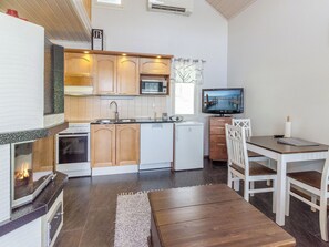 A compact kitchen with a microwave, stove, and sink. There's a small dining area with a table and chairs.