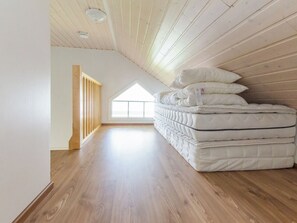 A spacious attic room with wooden floors and sloped ceilings, featuring a large skylight and a stack of mattresses. - Kotaniemi by Interhome (Lieksa)