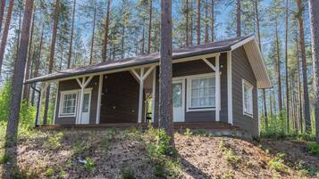 A cabin with a porch, surrounded by tall trees.