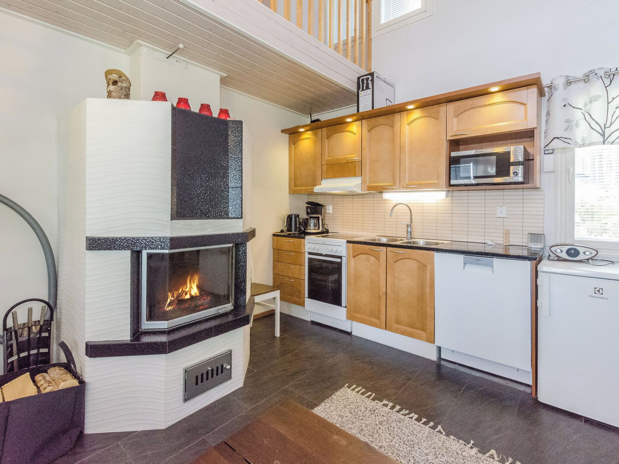 A modern kitchen with a built-in fireplace, wooden cabinets, a microwave, and a dishwasher.