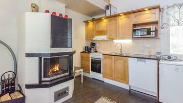 A modern kitchen with a built-in fireplace, wooden cabinets, a microwave, and a dishwasher.