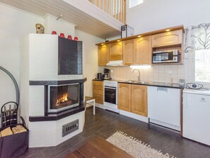 A modern kitchen with a built-in fireplace, wooden cabinets, a microwave, and a dishwasher.