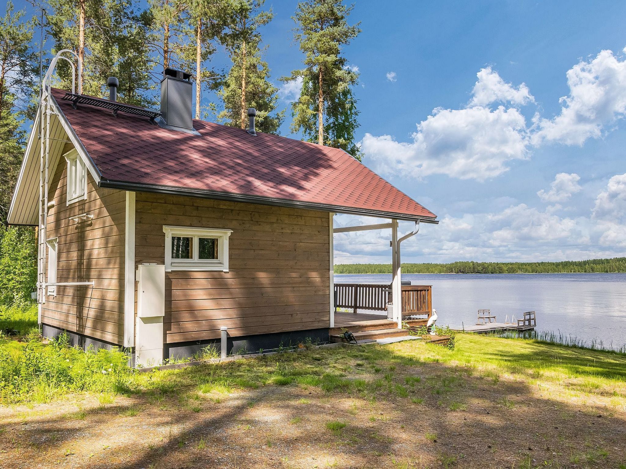 Eine Hütte mit rotem Dach, einer Veranda und Blick auf einen See.