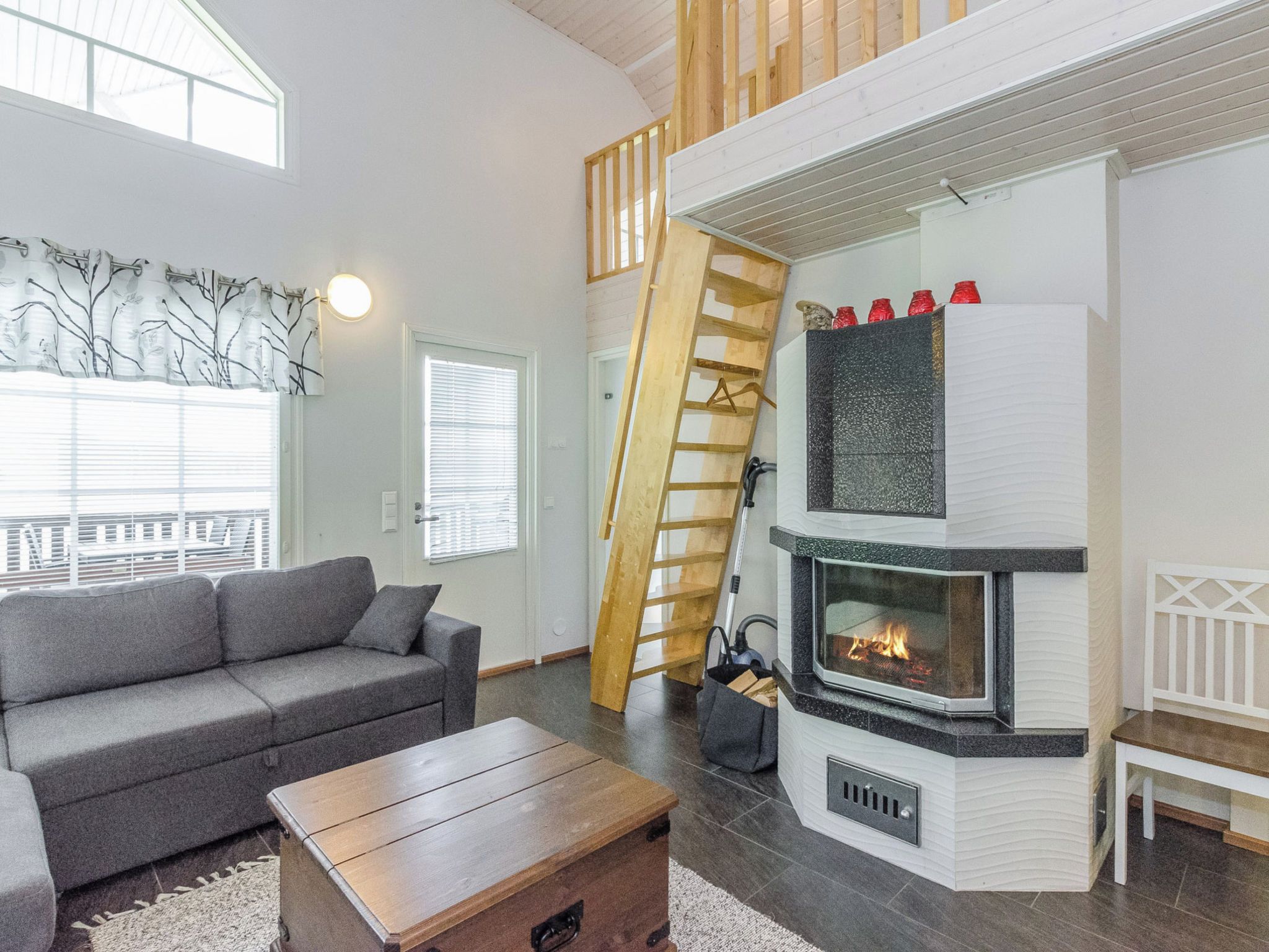A modern living room with a fireplace, a sofa, a coffee table, and a wooden ladder.