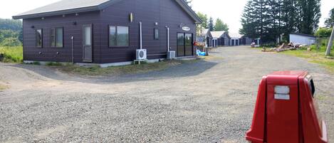 A small, single-story building with a dark facade, a sloped roof, and a gravel driveway.