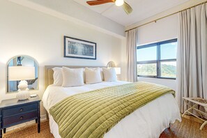 Relax in a spacious room with a large bed, round mirror, and ceiling fan.