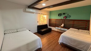 Ein Hotelzimmer mit zwei Betten, einem Sofa, einem Holzkopfstück, einem kleinen Tisch und einer Wandklimaanlage.