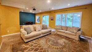 Una sala de estar con dos sofás color beige, un tapete estampado y un ventilador de techo.