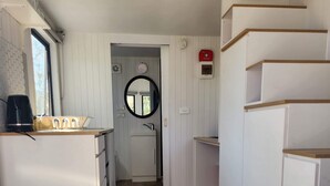 Una cocina compacta con muebles blancos, un lavamanos y una cafetera en la encimera.