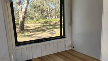 A room with a window overlooking a wooded area.