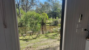 Vista desde una habitación con un balcón de madera que da a un área exterior con árboles y una masa de agua.