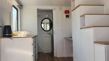 A compact, modern kitchen with white cabinetry, a wooden countertop, and a black coffee machine.
