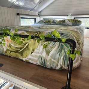 Une chambre avec un lit, une fenêtre et un support pour plantes.