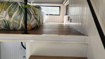 Een kleine kamer met een stapelbed, een klein raam en een wit toilet.