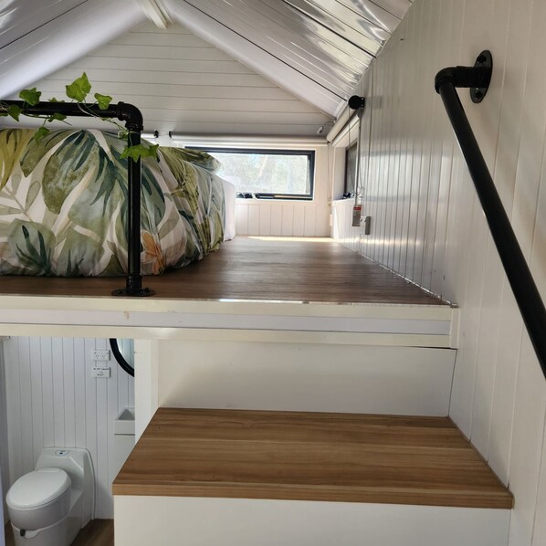 A compact room with a bunk bed, a small window, and a white toilet.