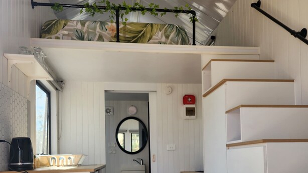 Cocina compacta y moderna con armarios blancos, encimera de madera y una cafetera negra.