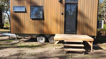 A small wooden cabin with a sliding door, a window, and a table with benches.