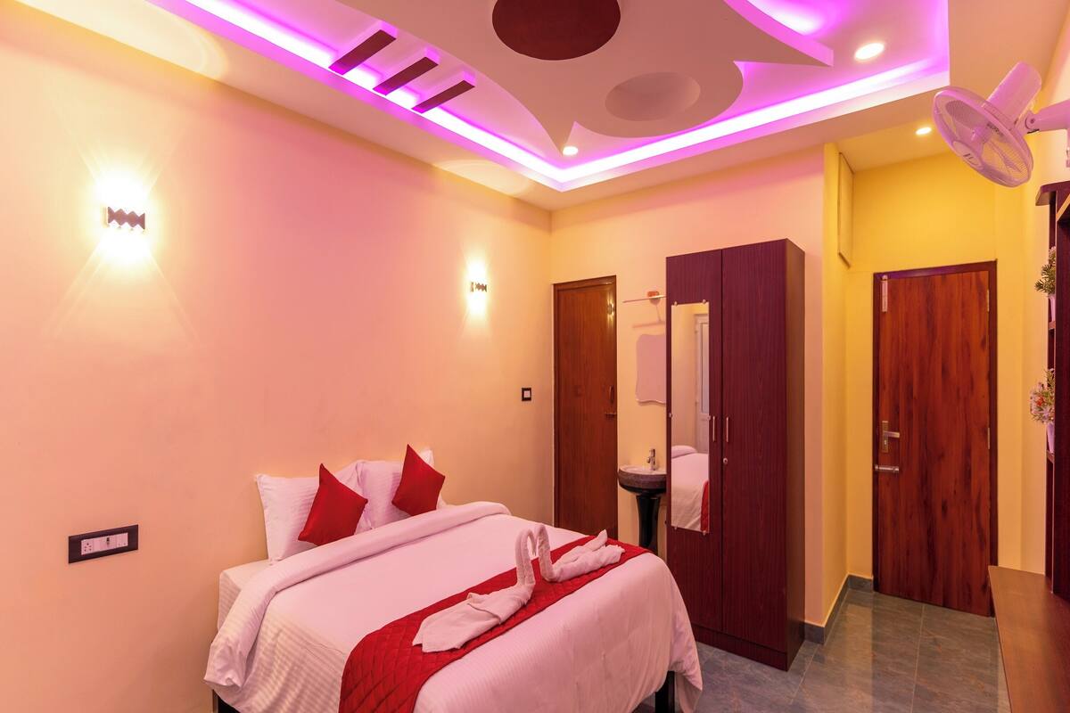 A hotel room with a bed, a mirror, a wardrobe, and a ceiling fan.