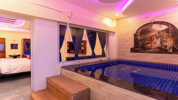 A hotel room with a private jacuzzi, a bed with red pillows, and a mural of a tiger. - Auro Beach Resort (Vanur)