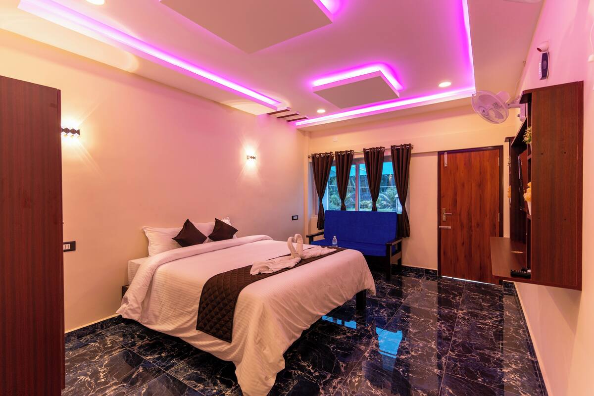 A modern hotel room with a large bed, a vanity, and a window with curtains.